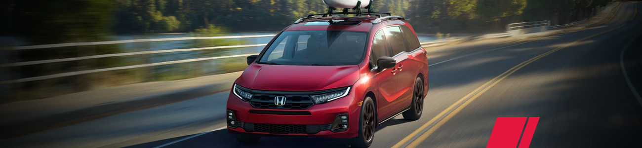 Red Honda Odyssey carrying a kayak on a road